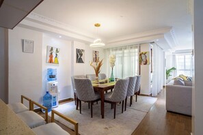 A dining area with a round table, six chairs, and a water dispenser. - Luxurious 4 Bedroom Apartment With a Rooftop Pool in Kilimani (Nairobi)