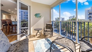 A balcony with a view of buildings, a clock, and a fish decoration. - Oceanfront 3BR Condo • Pool & Panoramic Views (New Smyrna Beach)