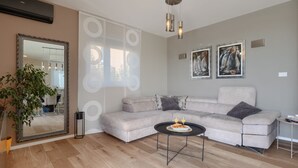 A living room with a sectional sofa, a round coffee table, a large mirror, and two paintings on the wall. - Vila PrivePolai by Villas Guide (Pula)