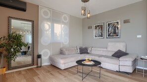 A living room with a sectional sofa, a round coffee table, a large mirror, and two paintings on the wall. - Vila PrivePolai by Villas Guide (Pula)