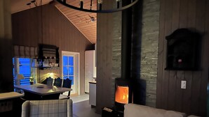 A cozy living room with a fireplace, a dining area with a table and chairs, and a kitchen with wooden cabinets. - Chalet /Hytte with dream view, pure relaxation in the beautiful nature (Telemark)
