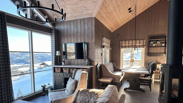 A cozy cabin interior with a large window offering a scenic view, a fireplace, and a comfortable seating area. - Chalet /Hytte with dream view, pure relaxation in the beautiful nature (Telemark)