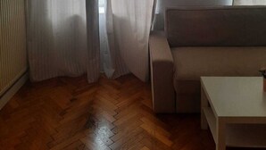 Une pièce avec un plancher en bois, un canapé beige et une table blanche.
