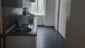 Une cuisine de taille réduite, équipée d’un évier, d’une cuisinière et d’une fenêtre.