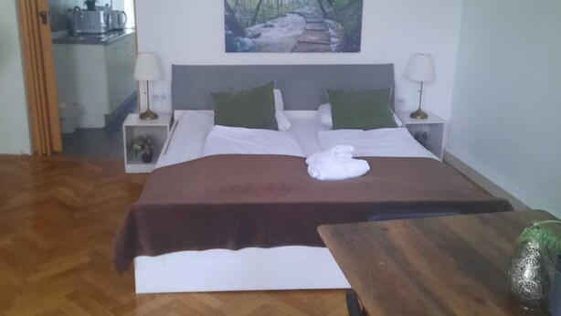 Une chambre à coucher avec un lit, deux tables de chevet, un tableau, une table en bois et une chaise.
