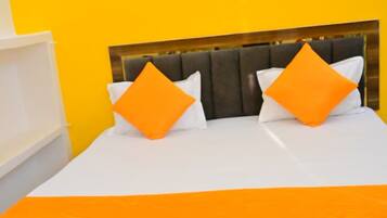 A bed with a wooden headboard, two orange pillows, and a white bedspread.