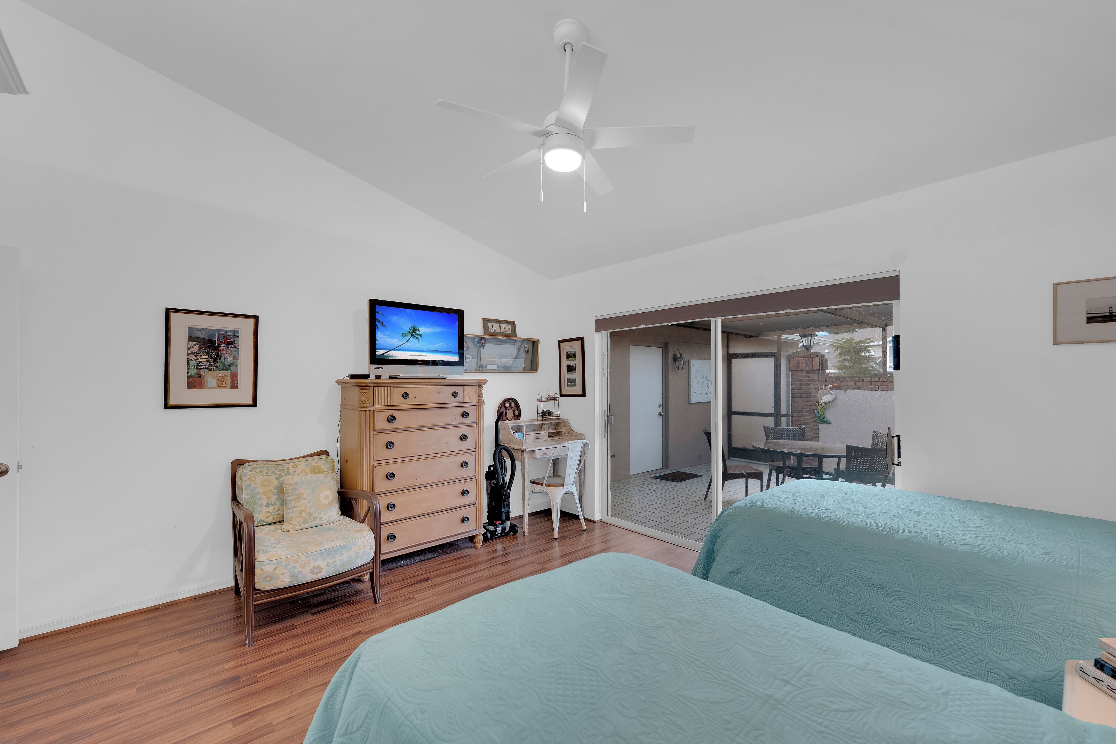 A bedroom with a bed, a desk, a chair, a dresser, and a television.