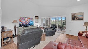 Ein modernes Wohnzimmer mit Ledersofas, einem Flachbildfernseher und Kunstwerken an den Wänden.