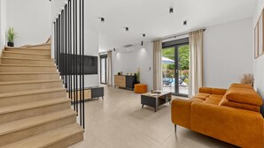 Una sala de estar moderna con una escalera, un sofá, una mesa de centro y un televisor.