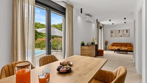 Un comedor moderno con una mesa de madera, sillas y vista a una piscina.