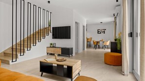 Una sala de estar moderna con una escalera, un comedor y una cocina.