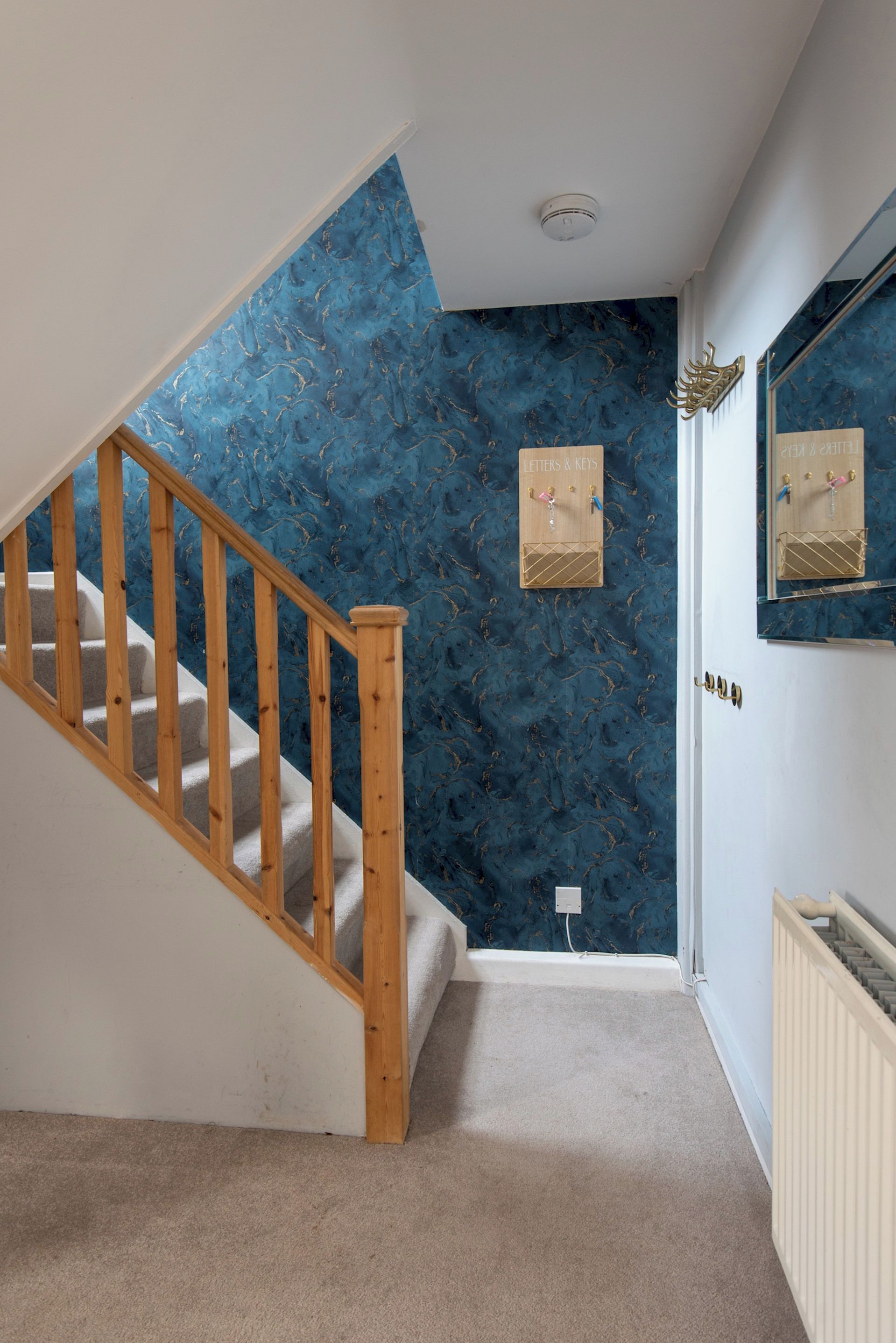 A staircase with wooden handrails leading to a landing with a blue marble wall.