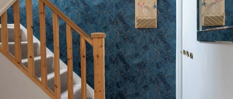 A staircase with wooden handrails leading to a landing with a blue marble wall.