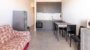 Una cocina compacta con comedor, sofá y refrigerador.