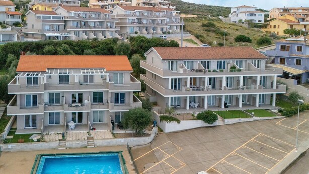 Un edificio residencial con piscina, varios balcones y zona de estacionamiento.