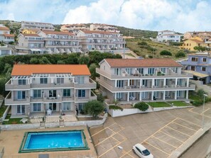 A residential building with a swimming pool, multiple balconies, and a parking area. - Apartment in With Swimming Pool and sea View (Castelsardo)