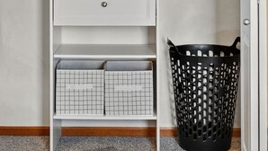Un vestidor amplio con estantes múltiples, una barra para colgar ropa y un cesto de ropa.