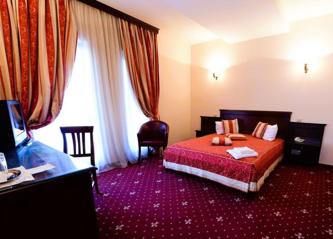 Ein Hotelzimmer mit Bett, Schreibtisch, Stuhl und Schreibtischlampe.