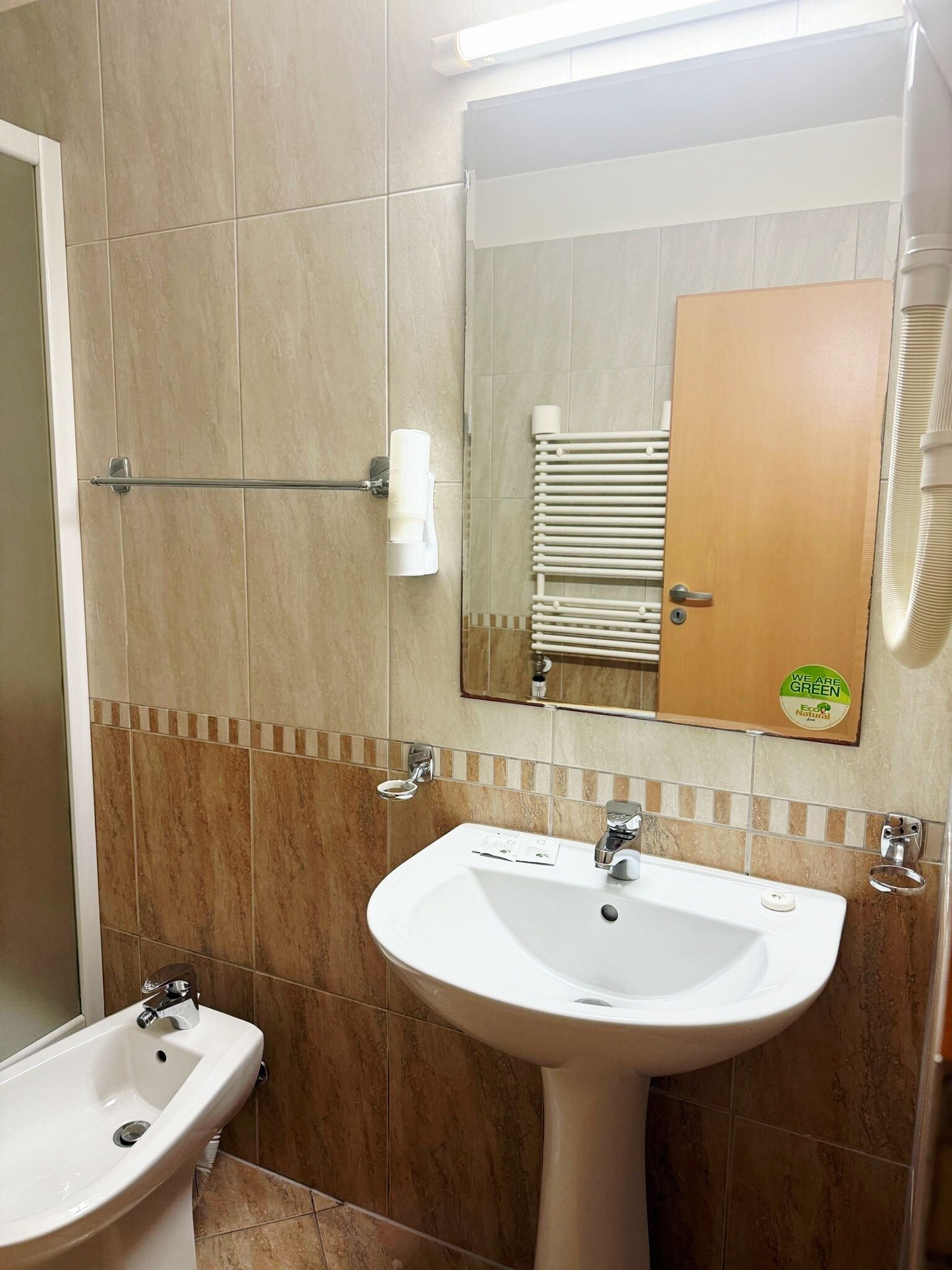 Un baño con lavamanos blanco, un espejo y un perchero para toallas.