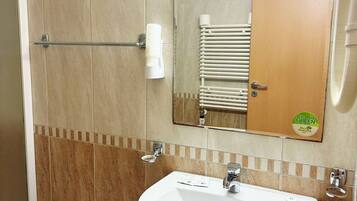 Une salle de bain avec un lavabo blanc, un miroir et un porte-serviettes.