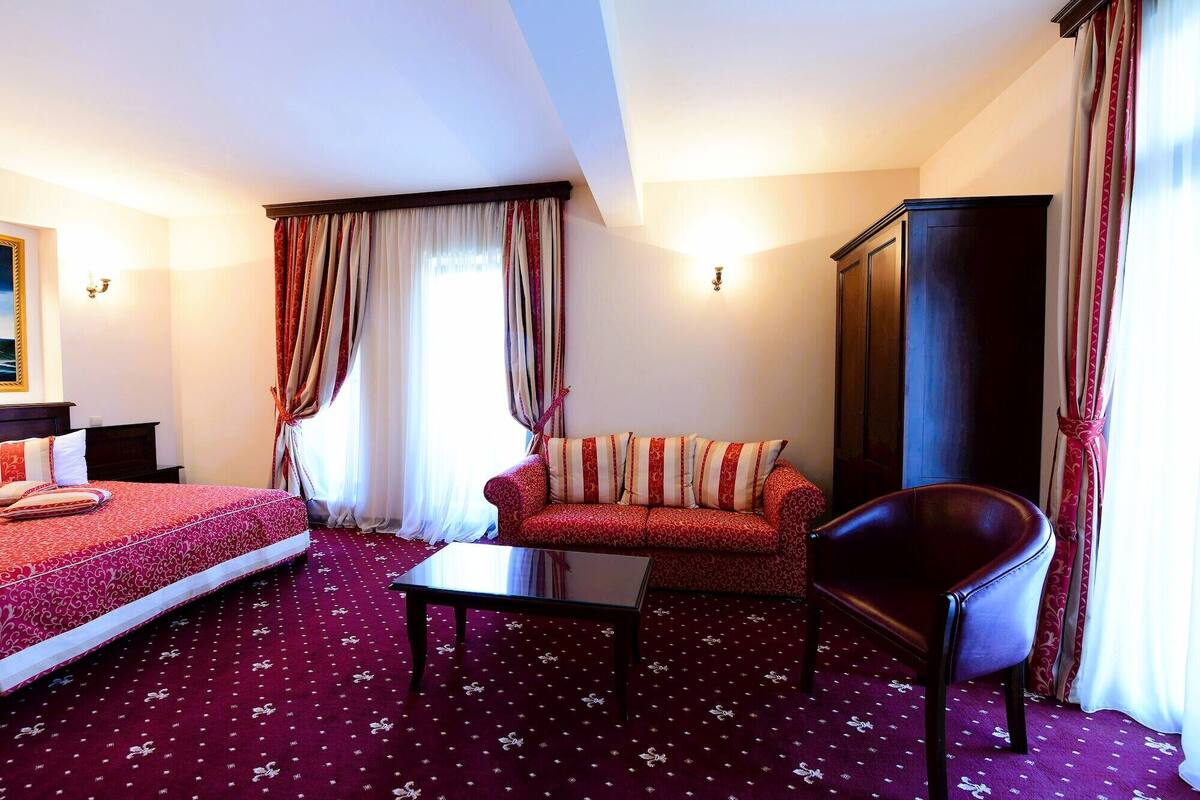 Una habitación de hotel con una cama, un sofá, una silla, una mesa y un armario.