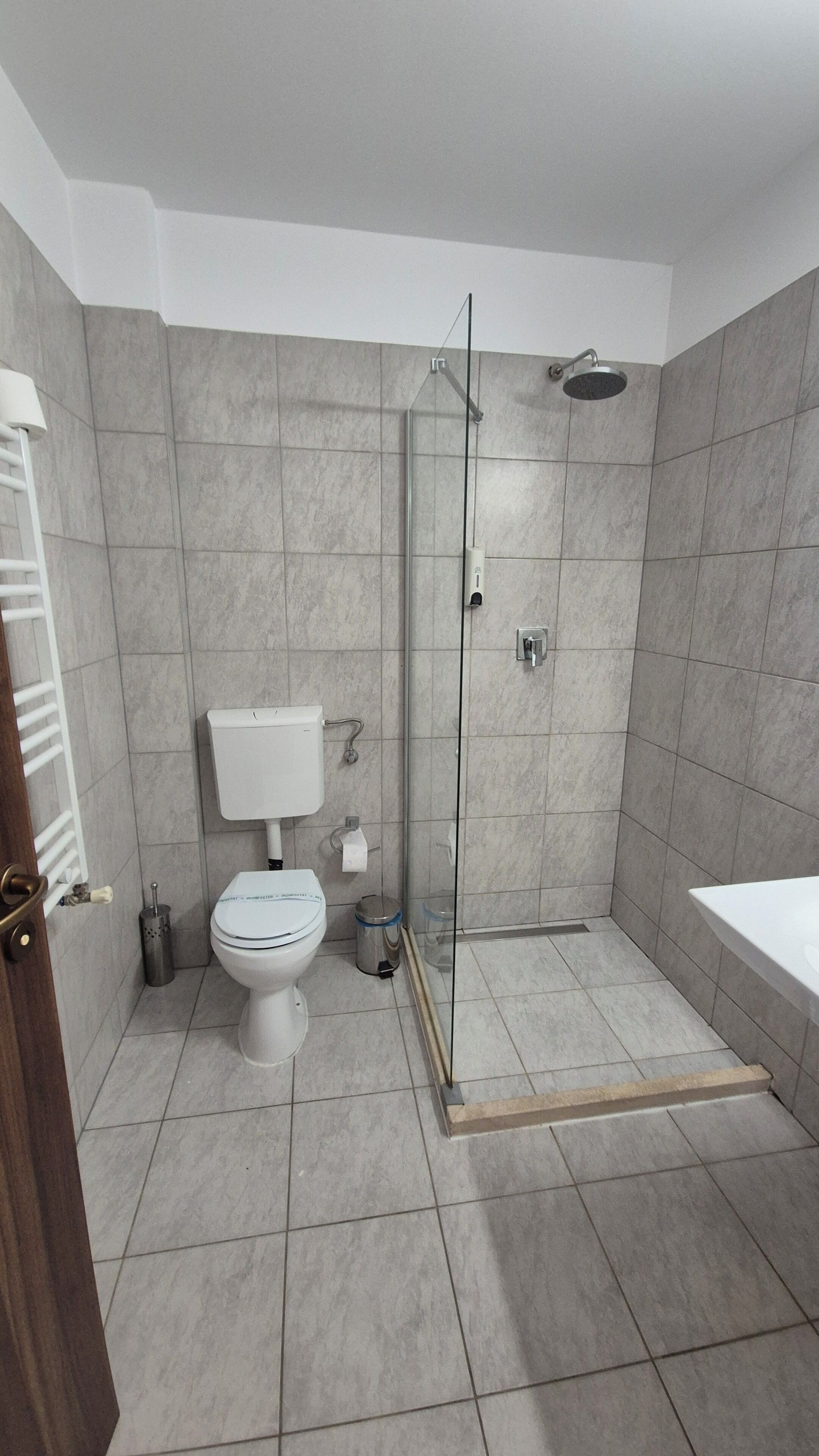 Een moderne badkamer met toilet, hygiëneschuimer en douche.