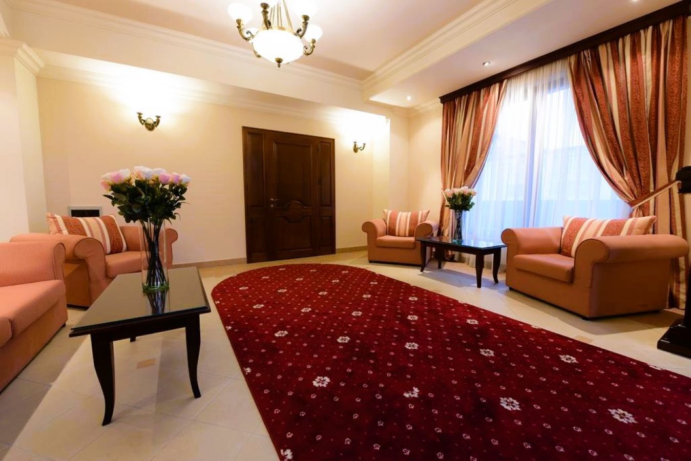 Ein Wohnzimmer mit zwei Sofas, einem Couchtisch, einem roten Teppich mit Blumenmuster und einer Kronleuchter.
