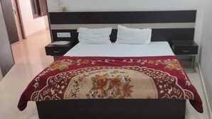 A hotel room with a bed, two bedside tables, and a nightstand. - Shree Radharaman Palace (Ayodhya)
