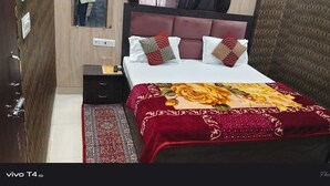 A bedroom with a bed, nightstand, and a red patterned rug. - Shree Radharaman Palace (Ayodhya)