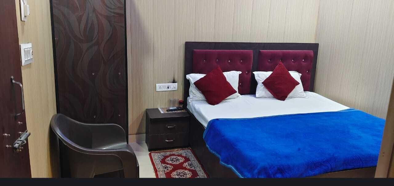 A hotel room with a bed, a nightstand, a chair, and a door.