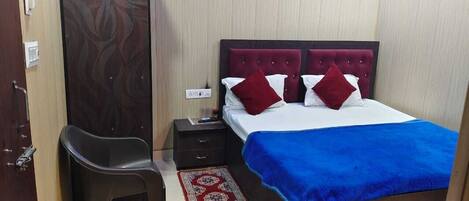 A hotel room with a bed, a nightstand, a chair, and a door.