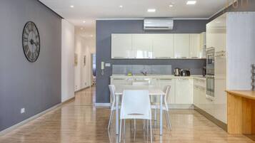 Une cuisine moderne avec des meubles blancs, un îlot central et un coin repas avec des chaises blanches.