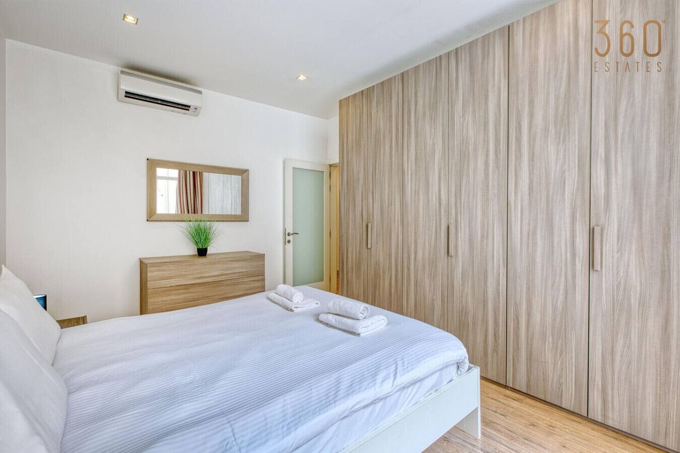 A bedroom with a bed, a bedside table, a mirror, and a wardrobe.