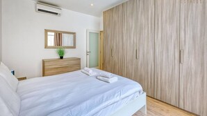Ein Schlafzimmer mit einem Bett, einem Nachttisch, einem Spiegel und einem Kleiderschrank.