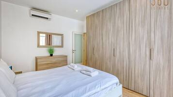 A bedroom with a bed, a bedside table, a mirror, and a wardrobe.