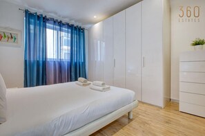 Ein Schlafzimmer mit einem Bett, einem weißen Kleiderschrank und einem Fenster mit blauen Vorhängen.