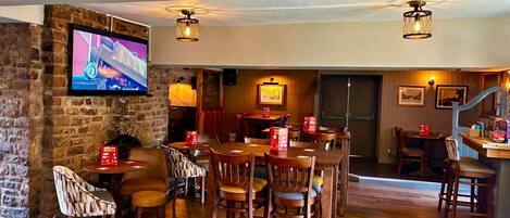 A restaurant with wooden furniture, a stone wall, and a television mounted on the wall.