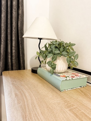 A wooden bedside table with a lamp, a potted plant, and a book. - The Cozy Settle Stay - Relax and Unwind, 2 bedroom apartment near central London (London)
