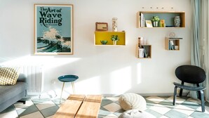 Un salón con un sofá, una mesa de centro, una silla y estanterías con adornos.