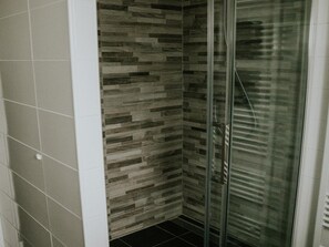 A shower with a glass door and a tiled wall with a wood-like pattern. - Luxury Holiday Loft in Si-es-an (Balkbrug)