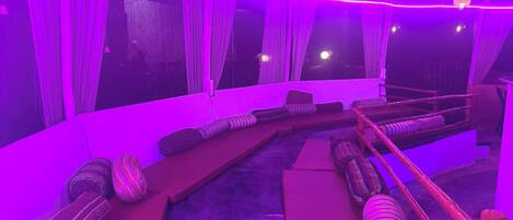 A room with a curved seating area, a small pool, and a ceiling with a grid-like structure.