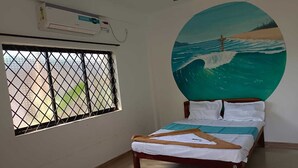 Ein Schlafzimmer mit Bett, einem Fenster mit Metallgitter, einer Klimaanlage und einem Strandbild.