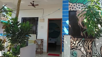 Una habitación con cama, ventilador de techo y puerta que da a otra estancia.