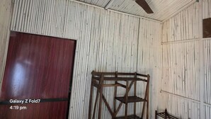 Ein Zimmer mit wellenförmigen Metallwänden, einer Holztür und einem Deckenventilator.