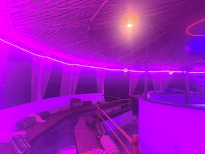 A room with a curved seating area, a bar counter, and a hanging light fixture. - Salvador Beach Cafe (Arambol)