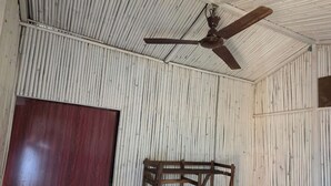 A room with corrugated metal walls, a wooden door, and a ceiling fan. - Wood Castle Arambol (Arambol)