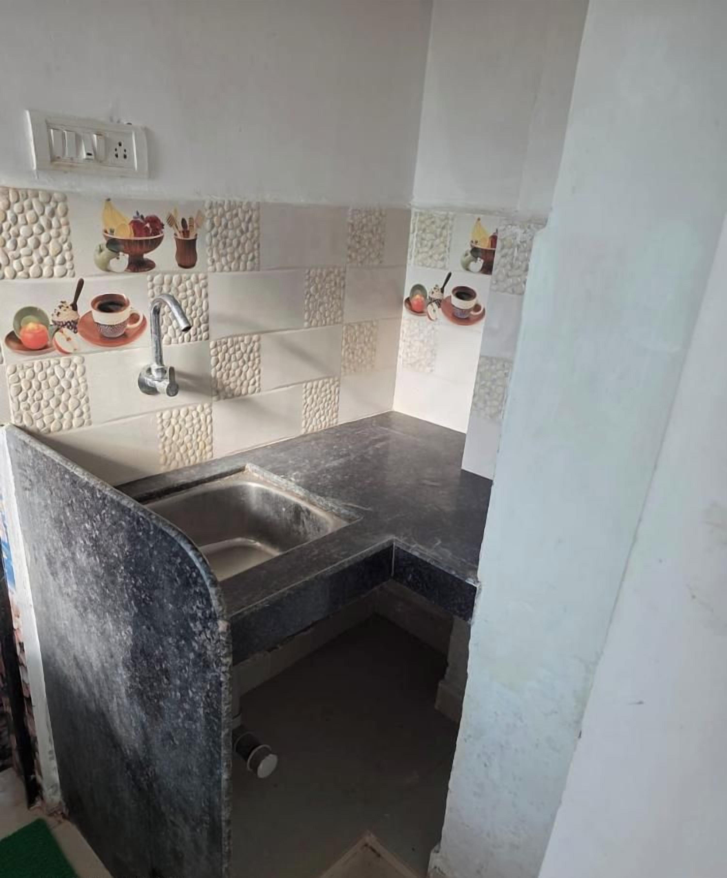 A compact kitchen with a sink, a countertop, and decorative tiles.