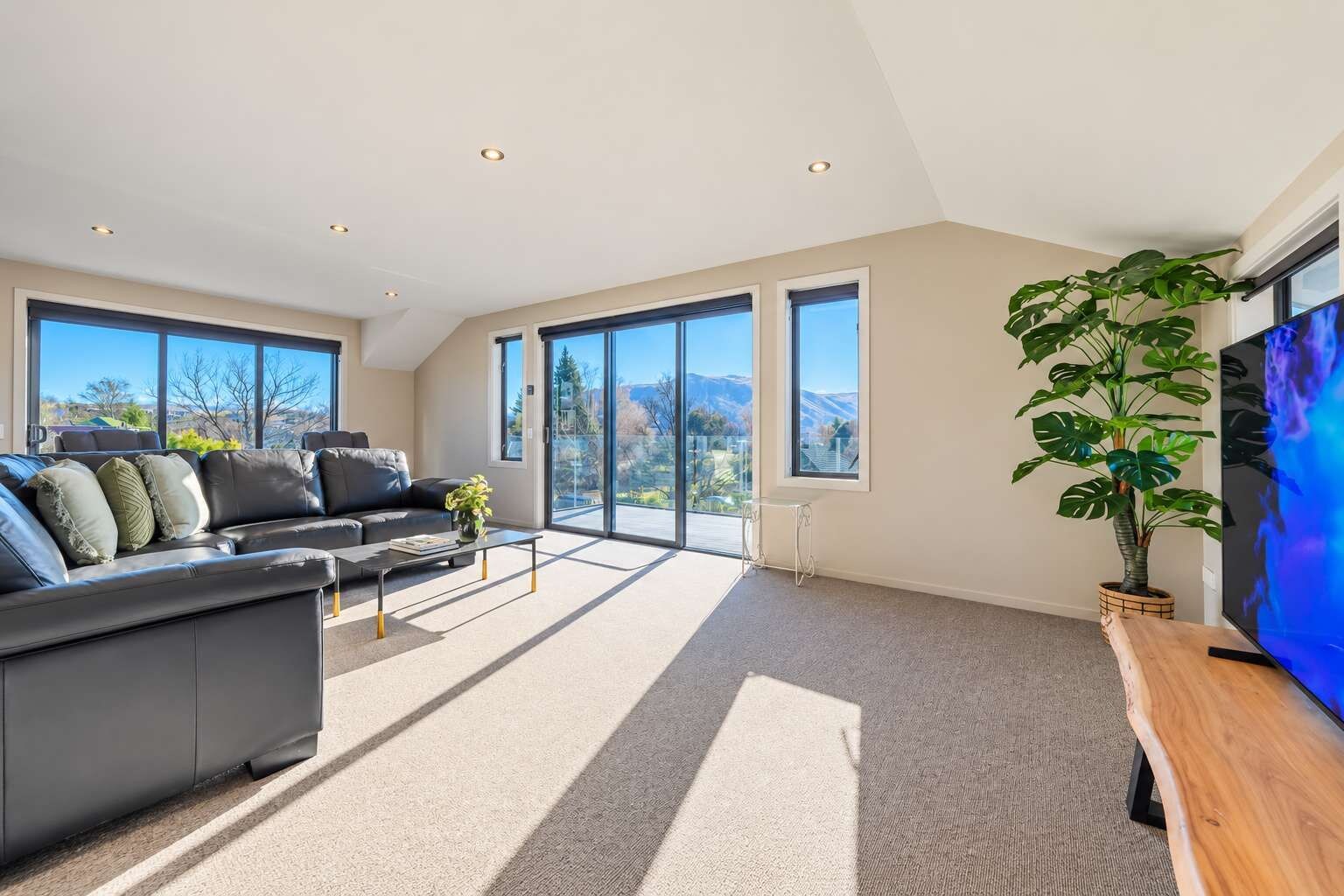 A modern living room with a sofa, coffee table, and a TV on a wooden stand.