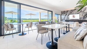 A modern dining area with large windows, outdoor umbrellas, and a view of the countryside. - Royal Tiki Lodges (Plaissan)