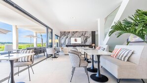A modern dining area with a view of the countryside, featuring a sofa, dining tables, and chairs. - Royal Tiki Lodges (Plaissan)